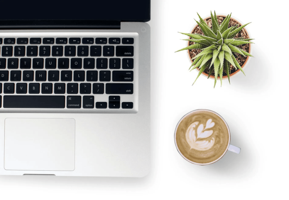 Laptop on a desk with a cup of coffee and a plant